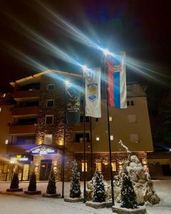 un edificio con banderas en la nieve por la noche en Iskra na Zlataru, en Nova Varoš