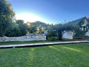 una casa con una valla blanca y un patio en HOTELPRATERVGB en Villa General Belgrano