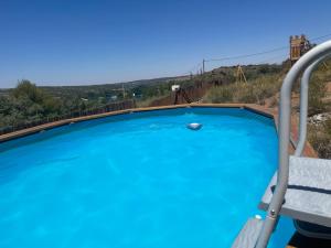 a blue swimming pool with a chair and a bridge at El Balcón del Rey in Ruidera
