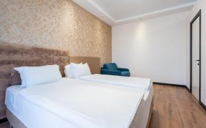 a bedroom with a large white bed and a blue chair at Olympus Hotel By Umbrella in Tbilisi City