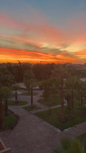 een zonsondergang boven een park met bomen en een pad bij Appartement Hivernage M Avenue in Marrakesh