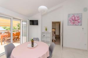 a white dining room with a table and chairs at Apartments A-Z in Stara Novalja