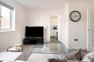 a living room with a tv and a couch and a clock at Immaculate 2-Bed Apartment in Welwyn Garden City in Welwyn Garden City