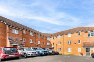 een rij auto's geparkeerd voor een bakstenen gebouw bij Immaculate 2-Bed Apartment in Welwyn Garden City in Welwyn Garden City