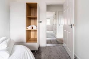 a white bedroom with a bed and a hallway at Immaculate 2-Bed Apartment in Welwyn Garden City in Welwyn Garden City
