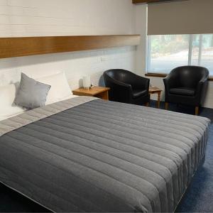 a bedroom with a large bed and two chairs at Orana Motor Inn in Mildura