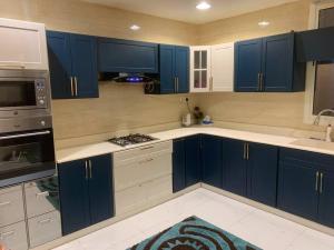 une cuisine avec des armoires bleues et des comptoirs blancs dans l'établissement شقه انيقه وموقع مميز, à Dammam