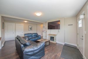 a living room with a leather couch and a fireplace at Lakeviews, big yard/deck, minutes to Silver Star/Golf/Wineries. in Vernon