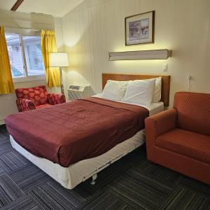 une chambre d'hôtel avec un lit et une chaise dans l'établissement Home Motel Abbotsford, à Abbotsford