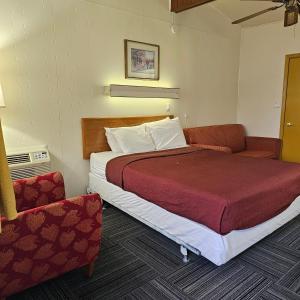 a hotel room with a bed and a chair at Home Motel Abbotsford in Abbotsford