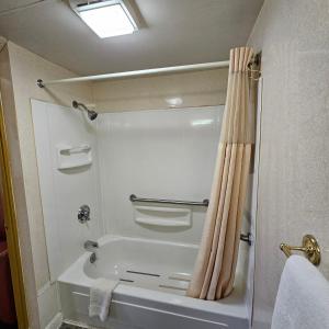 a bathroom with a bath tub and a shower curtain at Home Motel Abbotsford in Abbotsford