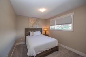 1 dormitorio con cama blanca y ventana en Lakeviews, big yard/deck, minutes to Silver Star/Golf/Wineries. en Vernon