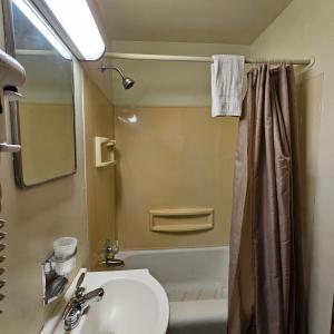 La salle de bains est pourvue d'un lavabo, de toilettes et d'une douche. dans l'établissement Home Motel Abbotsford, à Abbotsford