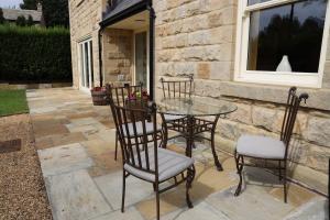 a patio with a glass table and four chairs at Bridge House Farm in Weeton