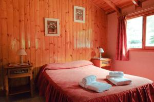 1 dormitorio con 1 cama con 2 toallas en Cabañas Mijos en El Bolsón