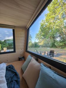 a room with a bed and a large window at Moose home Tiny house AMBUR in Saint-Jacques-dʼAmbur