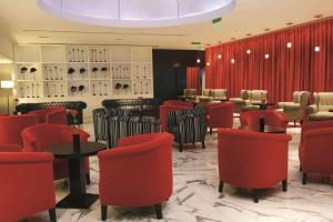 a waiting area with red chairs and tables in a salon at NH Buenos Aires Tango in Buenos Aires