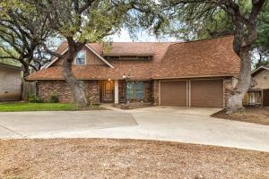 a brick house with a driveway and two trees at Wanderlust - A Birdy Vacation Rental in San Antonio