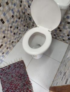 a bathroom with a white toilet with a rug at CASA EM PRAIA SECA in Araruama