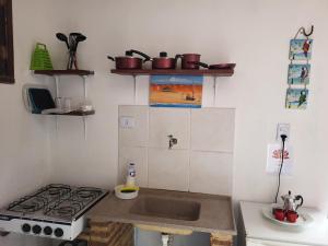a small kitchen with a stove and a sink at Chalé Flor do Ser in Canoa Quebrada