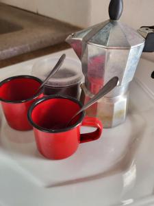 three red cups sitting on a counter with spoons at Chalé Flor do Ser in Canoa Quebrada