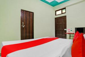 - une chambre avec un lit rouge et blanc et une porte dans l'établissement OYO Flagship Green Well Hotel & Restaurant, à Rewāri