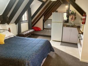 a bedroom with a bed and a kitchen with a refrigerator at Arden Country House - The Chalet Bed and Breakfast in Dunedin