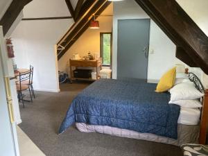 1 dormitorio con 1 cama azul en el ático en Arden Country House - The Chalet Bed and Breakfast en Dunedin