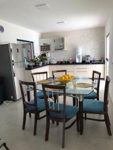a kitchen with a glass table and chairs and a kitchen with a refrigerator at Casa Primavera aluguel temporada in Paripueira
