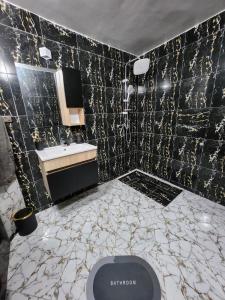 baño con lavabo y pared negra en Villa mgm, en Bou Mkila