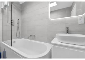a white bathroom with a tub and a sink at Lovely 4 bedroom with Outdoor space! in London