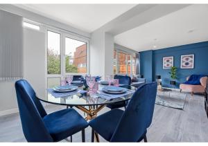 a dining room with a glass table and blue chairs at Lovely 4 bedroom with Outdoor space! in London