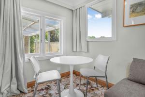 a living room with a table and chairs and two windows at Farley Avenue Turret & Lounge in Greytown
