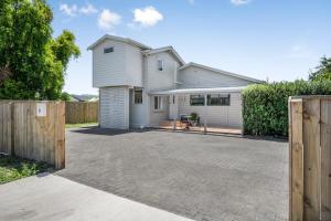 a white house with a fence and a driveway at Farley Avenue Turret & Lounge in Greytown