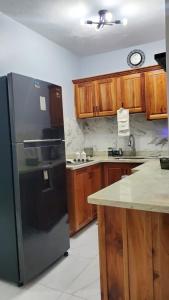 a kitchen with a black refrigerator and wooden cabinets at The shores in Montego Bay