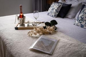 a book on a bed with a bottle of wine and glasses at Studios Charmosos Granja Brasil Itaipava in Itaipava