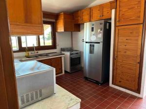 una cucina con frigorifero in acciaio inox e mobili in legno di Alojamiento en Punta del Este con vista al mar a Punta del Este Altre 12 foto