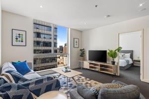 een woonkamer met een bank en een tv bij Nook Melbourne Apartments : Jane Bell Lane - Melbourne CBD in Melbourne