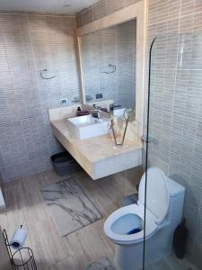 a bathroom with a toilet and a sink and a mirror at Maple Beach by DR Collection in Punta Cana