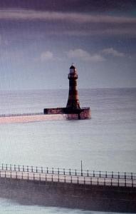a lighthouse sitting in the water next to a pier at The Hideaway - Apartment 8 in Sunderland