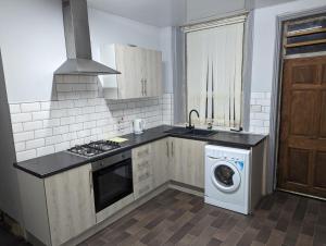 a kitchen with a stove and a washing machine at cozy double rm9 in Oldham