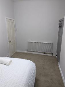 a white bedroom with a bed and a radiator at cozy double rm9 in Oldham