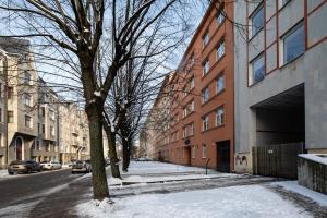 a snow covered street with buildings and a tree at Riga Embassy center Apartment with parking in Rīga