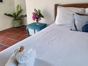 a white bed with a stuffed animal on it at Chalé Flor do Ser in Canoa Quebrada
