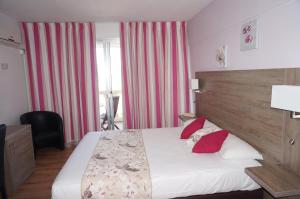 a bedroom with a large bed with red pillows at Logis Hotel Le Col De L'ange in Draguignan
