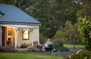 a woman sitting on a chair outside of a house at Straw House Farm - STANTHORPE in Dalveen