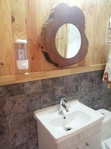 ein Bad mit einem Waschbecken und einem Spiegel in der Unterkunft Cabañas Rogelio in Liquiñe