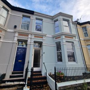 uma casa branca com uma porta azul em 4 Bed Park View House-Free Parking - Sleep 8 em Plymouth