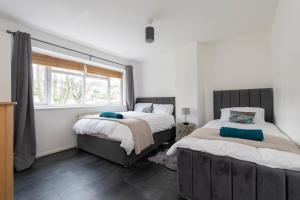 a bedroom with two beds and a window at Chingford charm great for families and contractors in Ponders End