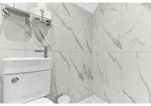 a white tiled bathroom with a toilet and a sink at GREAT 4BR House in London